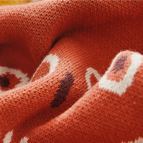 Close up of woven texture and burnt orange ethnic pattern on cotton throw fabric