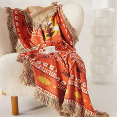 Cozy terracotta and yellow boho cotton throw draped over white armchair with white cup