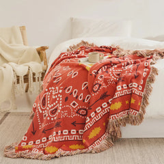 Terracotta boho cotton throw blanket with fringe styled on white bed in bedroom