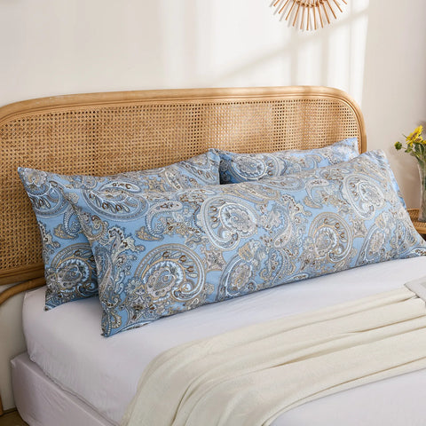 A pair of long blue paisley print cotton body pillows placed together on a bed, with a white blanket draped across the front.