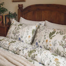 detailed view of two botanical print pillows against a classic dark wood headboard