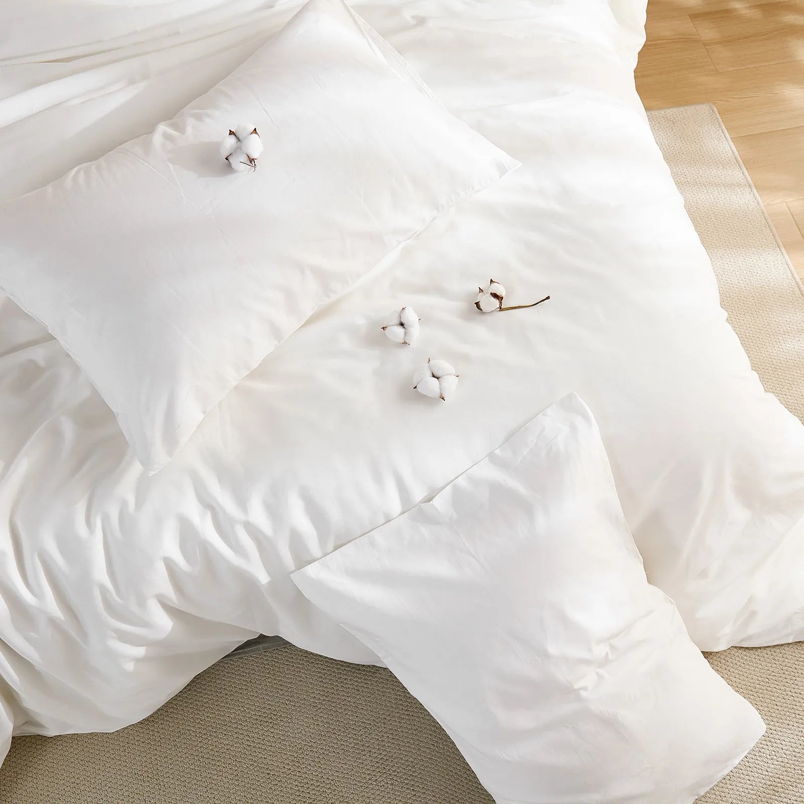 White solid duvet layout with four cotton blooms and two pillows